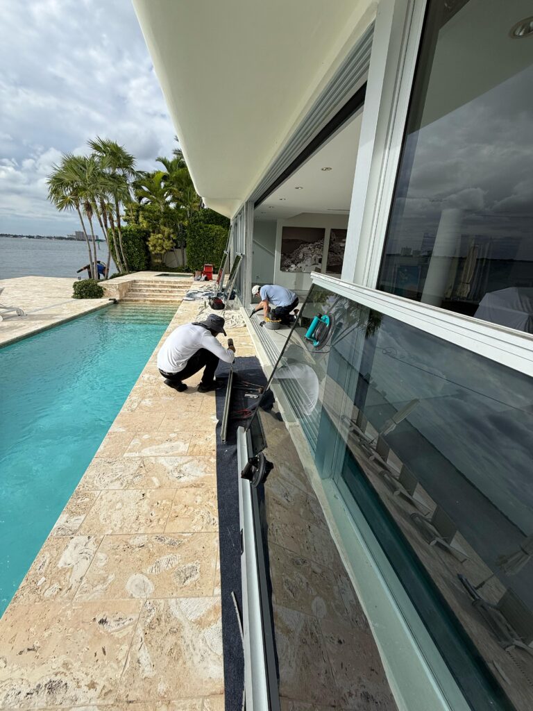 Professional technicians repairing a sliding glass door and replacing rollers in South Florida home